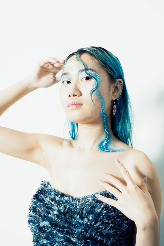 Artistic phot of a model with a streak of blue makeup and a fashionable dress to personify the idea of fluidity